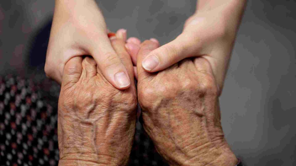A young and old wrinkled hands holding each other